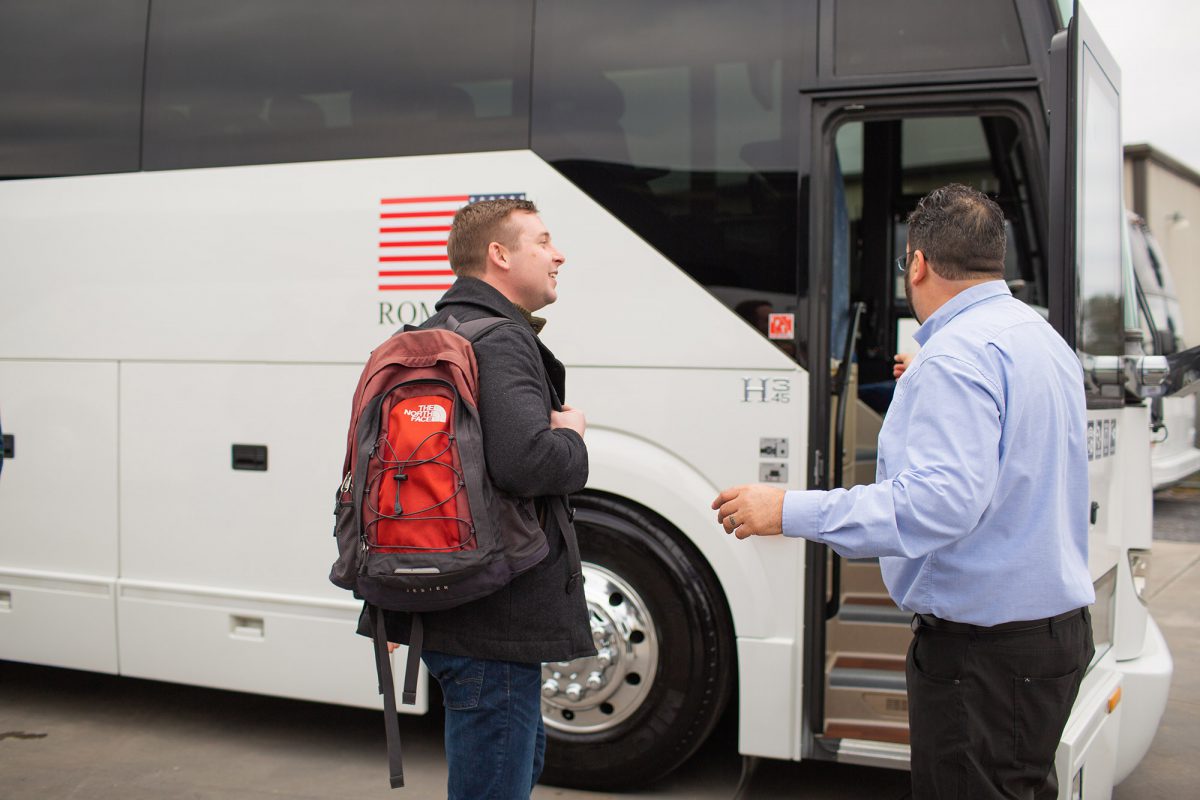 A man is greeted by a driver as he boards a bus