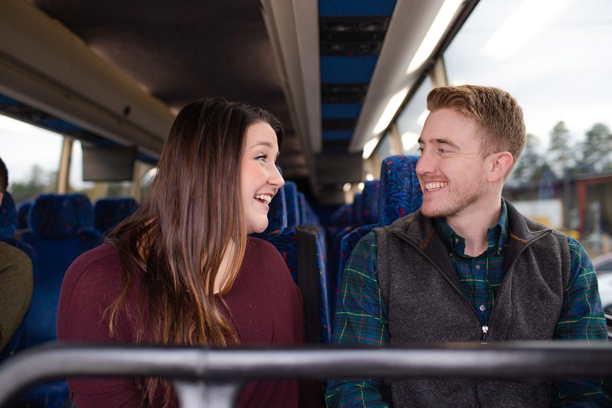 A man and woman talk on a bus